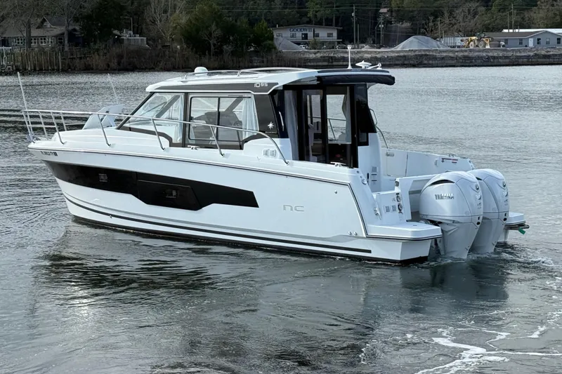 Slide: The Image of 2025 Jeanneau NC 1095 Coupe boat on calm water, featuring twin Yamaha engines. - 5