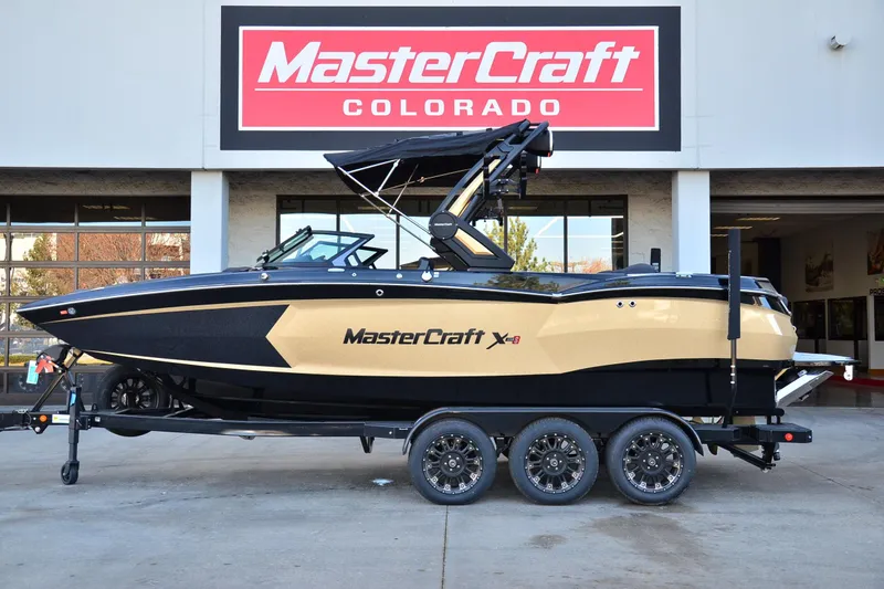 The Image of 2024 MasterCraft XStar S boat on trailer at dealership, side view. - 1