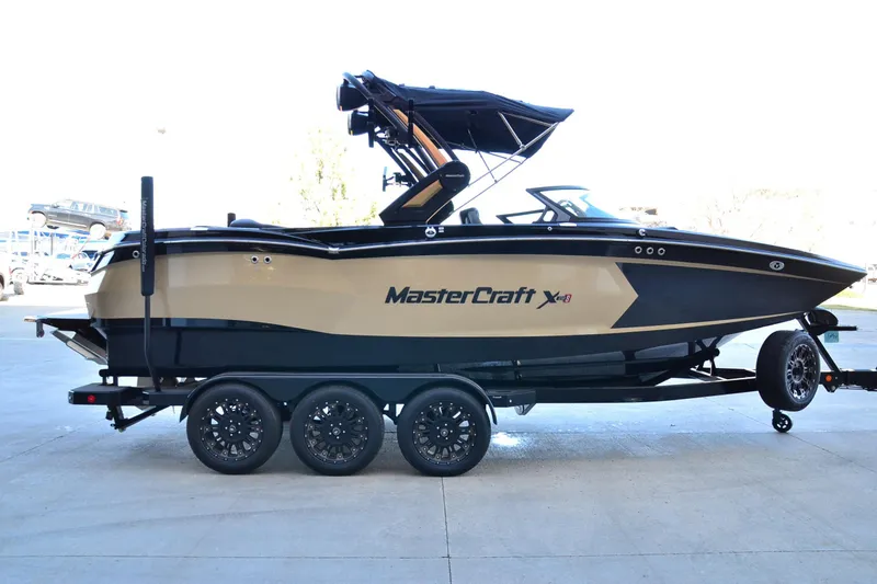 Slide: The Image of 2024 MasterCraft XStar S boat on trailer, side view, black and beige design. - 4