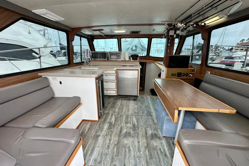 Slide: The Image of Interior of a 1976 Pacifica Flybridge boat with seating, kitchenette, and large windows. - 15