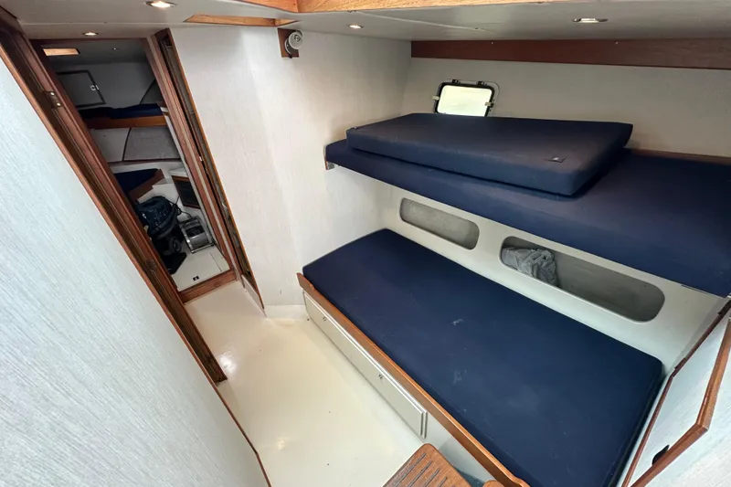 Slide: The Image of 1976 Pacifica Flybridge interior with blue cushioned bunks and wooden accents. - 30