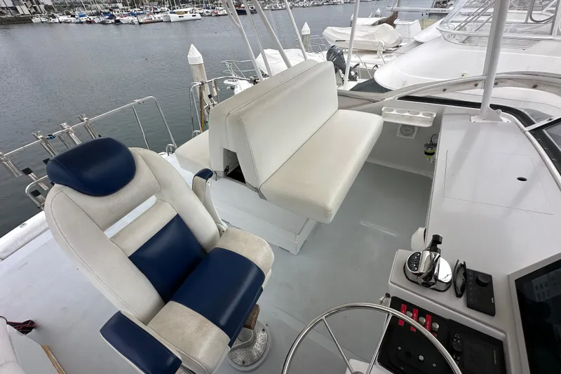 Slide: The Image of 1976 Pacifica Flybridge yacht interior with blue and white seating, overlooking marina. - 36