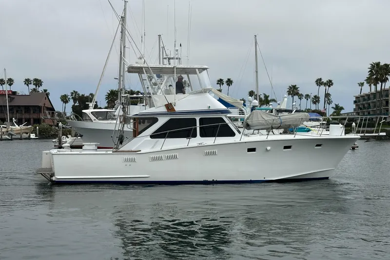 Slide: The Image of 1976 Pacifica Flybridge yacht docked in a marina with palm trees in the background. - 41