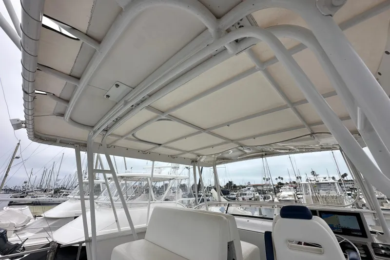 Slide: The Image of 1976 Pacifica Flybridge boat interior with marina view, featuring white seating and canopy. - 42