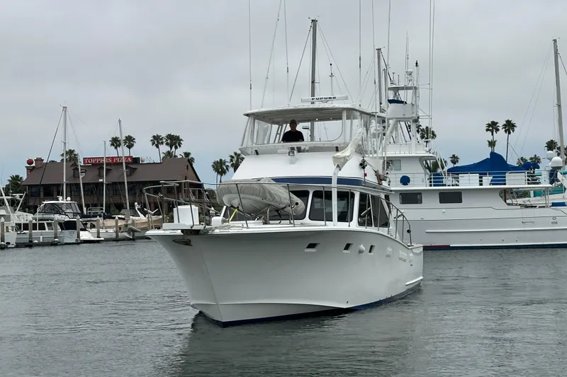 Slide: The Image of 1976 Pacifica Flybridge yacht docked in marina, with palm trees and buildings in background. - 5