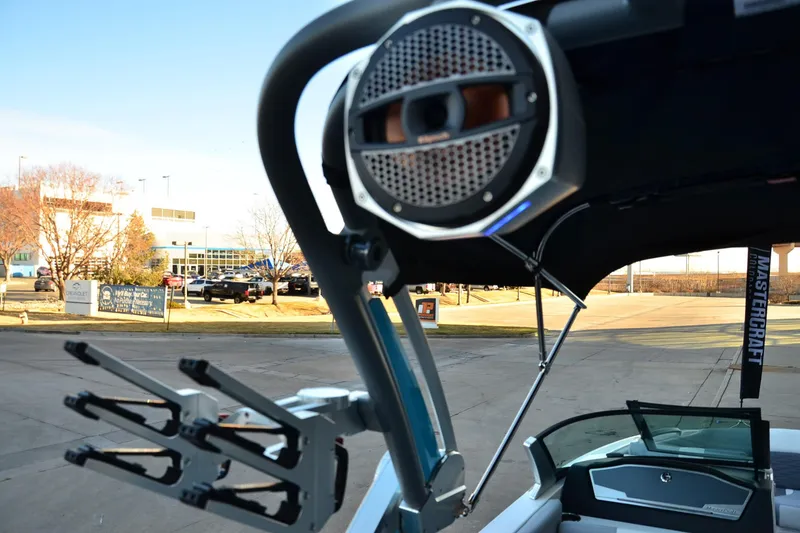Slide: The Image of 2024 MasterCraft X22 boat with speaker and wakeboard rack, parked outdoors. - 17