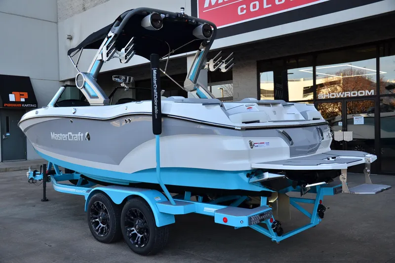 Slide: The Image of 2024 MasterCraft X22 boat on trailer outside showroom. - 2