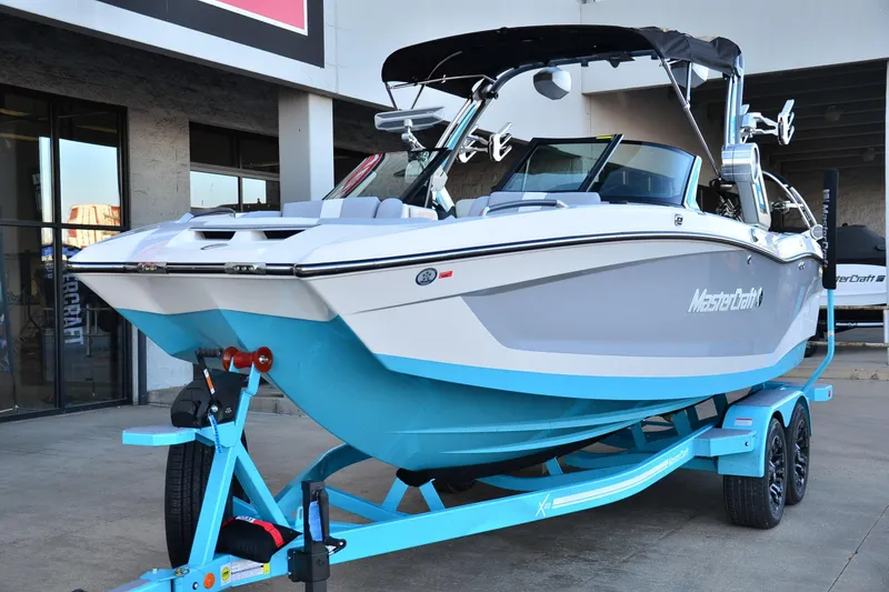 Slide: The Image of 2024 MasterCraft X22 boat on trailer, displayed outdoors. - 7