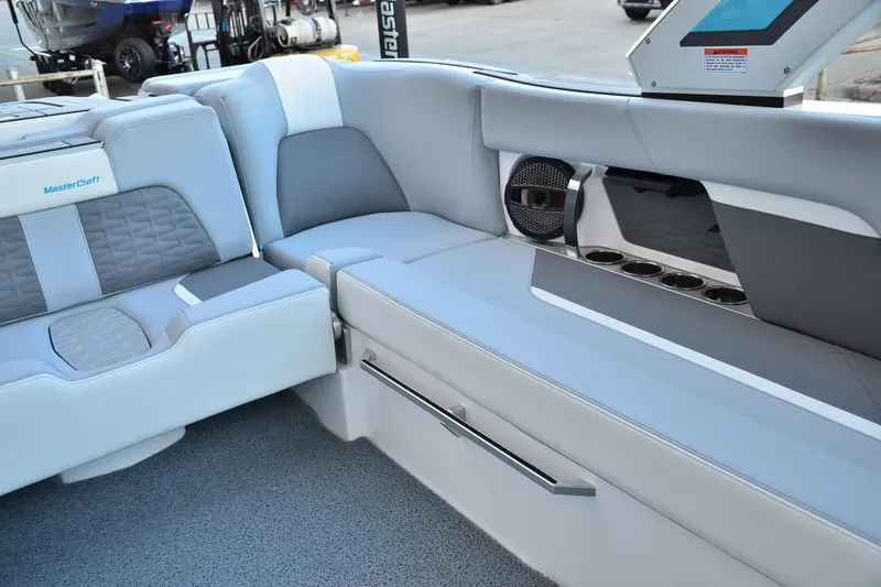 Slide: The Image of 2024 MasterCraft X22 boat interior with gray seating, cup holders, and speaker system. - 9