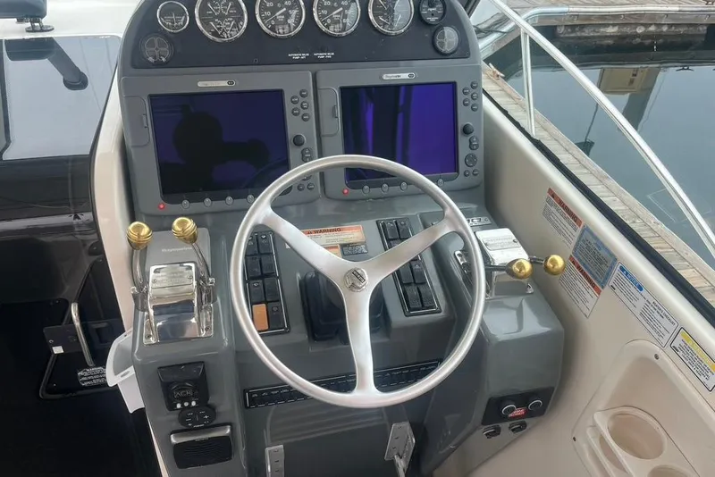 Slide: The Image of Control panel of a 2005 Pursuit 3100 Offshore boat with steering wheel and navigation screens. - 13