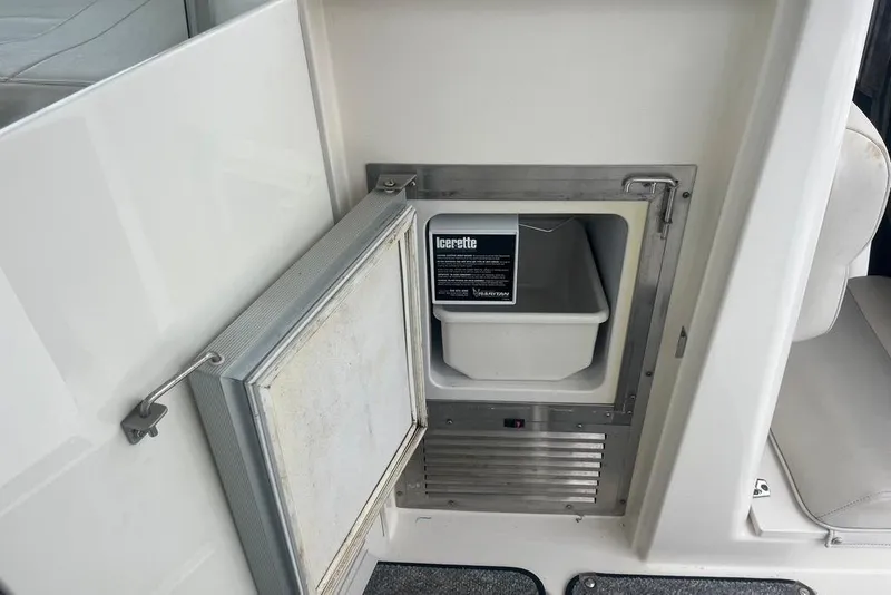 Slide: The Image of 2005 Pursuit 3100 Offshore boat ice maker compartment with open door. - 17