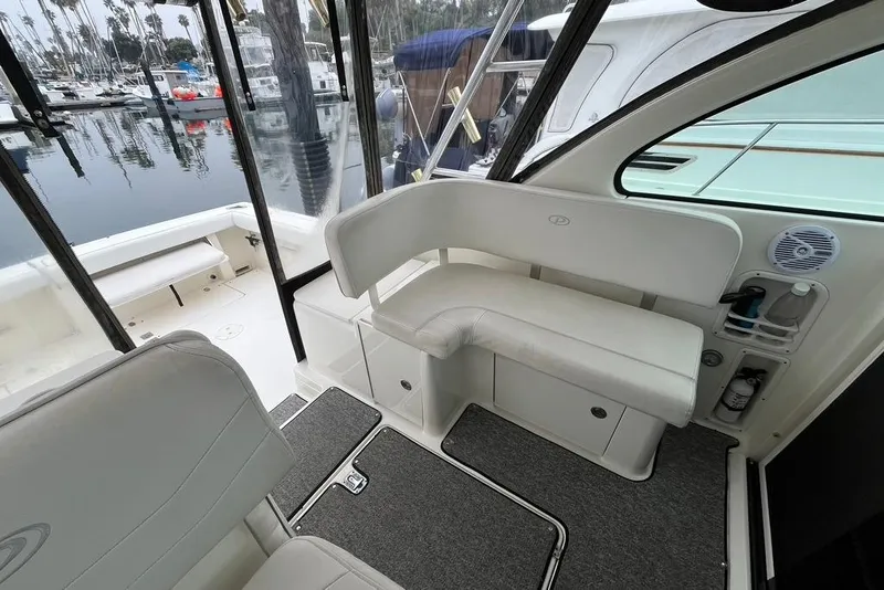 Slide: The Image of Interior of a 2005 Pursuit 3100 Offshore boat with white seating and marina view. - 18