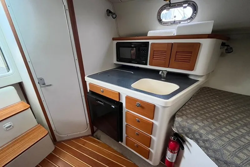 Slide: The Image of 2005 Pursuit 3100 Offshore boat interior with kitchenette, sink, and microwave. - 31