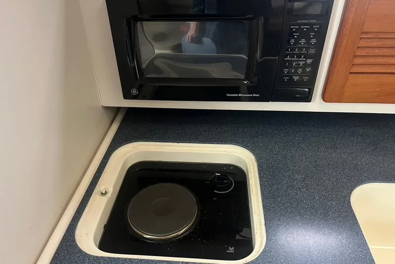 Slide: The Image of 2005 Pursuit 3100 Offshore kitchen with microwave and stove. - 34