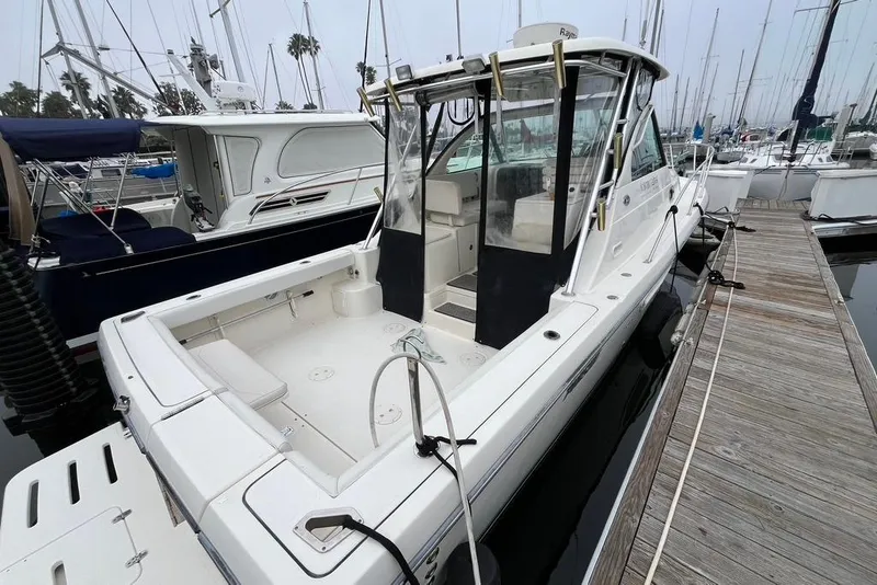 Slide: The Image of 2005 Pursuit 3100 Offshore boat docked at marina, showcasing spacious deck and sleek design. - 4