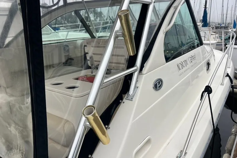 Slide: The Image of 2005 Pursuit 3100 Offshore boat docked, featuring sleek design and rod holders. - 44