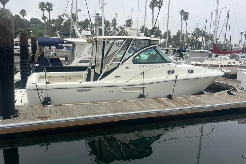 Slide: The Image of 2005 Pursuit 3100 Offshore boat docked at a marina with palm trees in the background. - 6