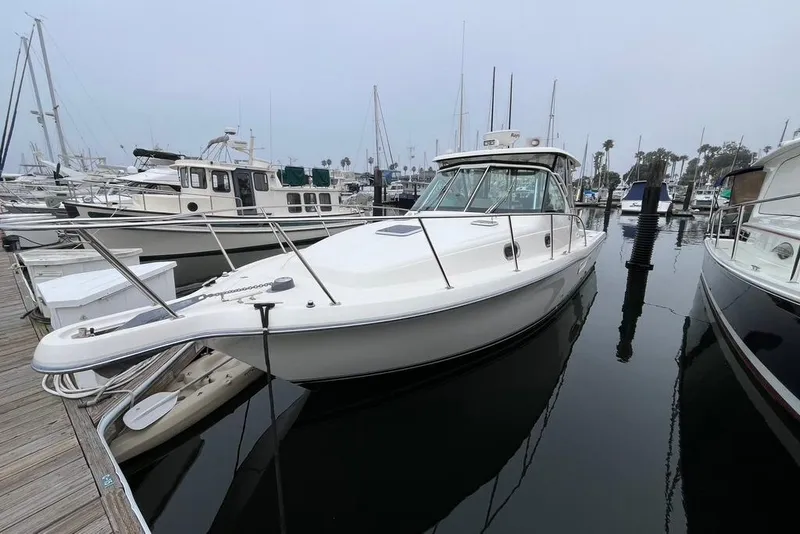 Slide: The Image of 2005 Pursuit 3100 Offshore boat docked in a marina, surrounded by other vessels. - 8