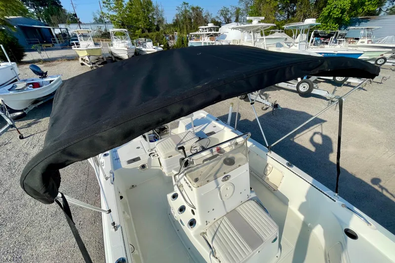 Slide: The Image of 2005 Sailfish 1900 BB Bay Boat with black canopy in a boatyard setting. - 22