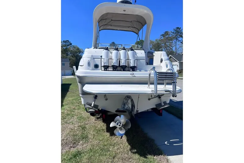 Slide: The Image of 2008 Larson Cabrio 260 boat, rear view with propeller and ladder, parked on grass. - 1