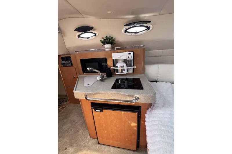 Slide: The Image of 2008 Larson Cabrio 260 boat interior with kitchenette, featuring sink, stove, and mini fridge. - 16
