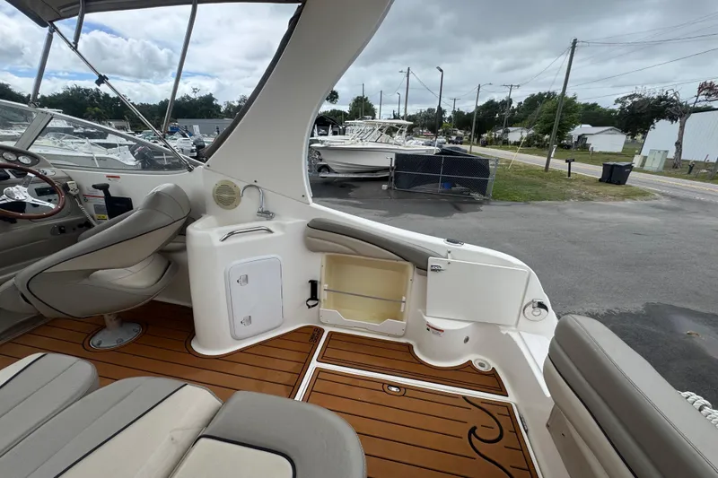 Slide: The Image of 2008 Larson Cabrio 260 boat interior with seating and wood flooring, parked outdoors. - 19