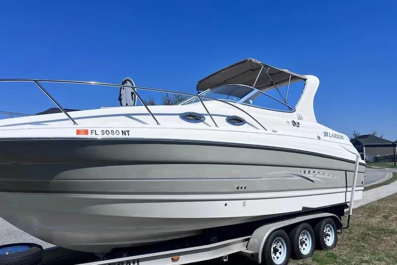 Slide: The Image of 2008 Larson Cabrio 260 boat on trailer under clear blue sky. - 2