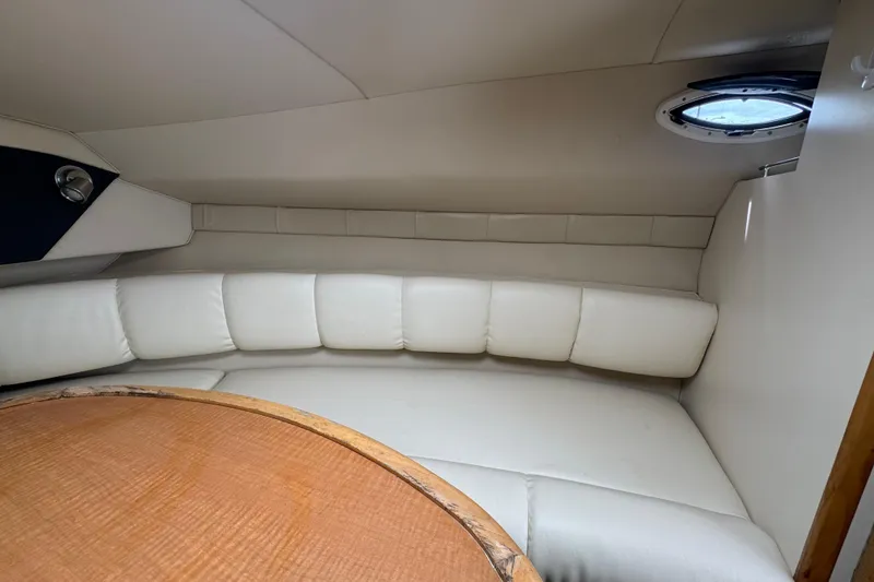 Slide: The Image of Interior of 2008 Larson Cabrio 260 boat with white leather seating and wooden table. - 34