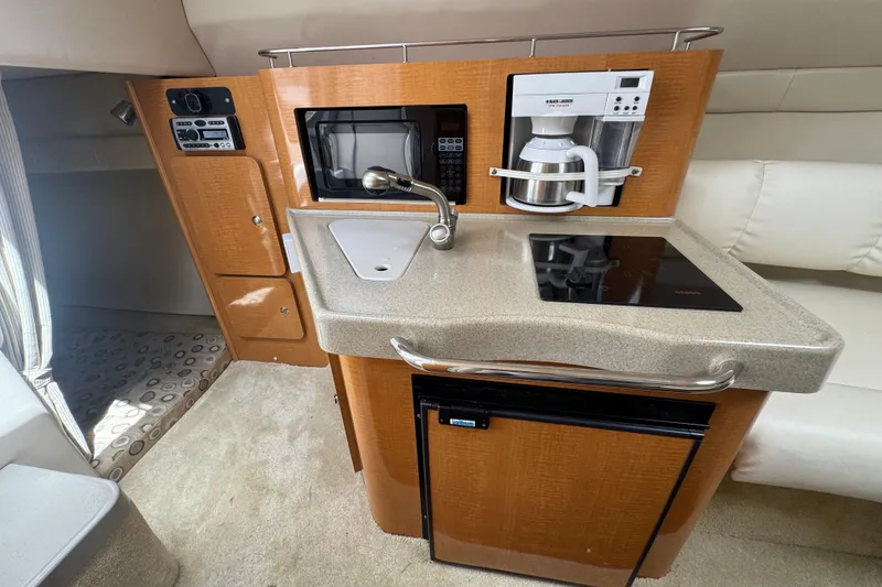 Slide: The Image of Compact kitchen area in a 2008 Larson Cabrio 260 boat with sink, stove, and appliances. - 37