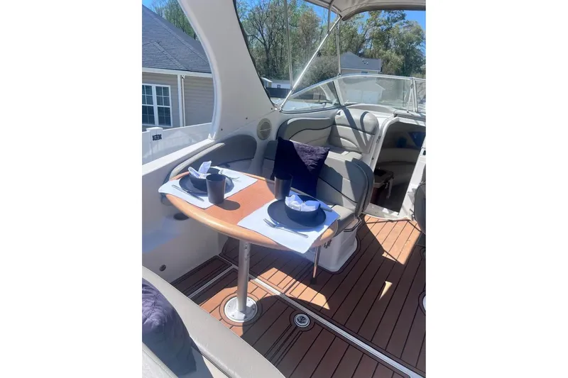 Slide: The Image of 2008 Larson Cabrio 260 boat interior with dining setup on wooden deck. - 7