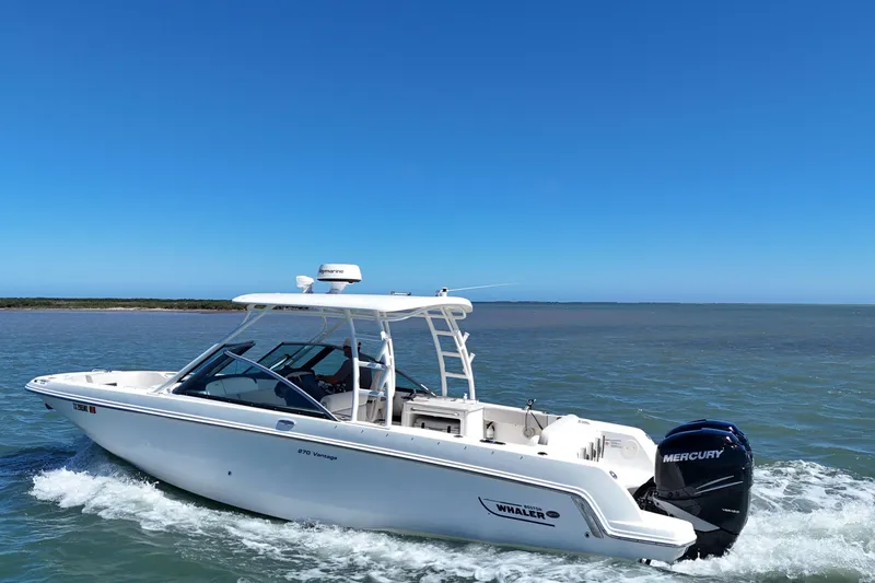 Slide: The Image of 2017 Boston Whaler 270 Vantage cruising on open water under clear blue sky. - 16