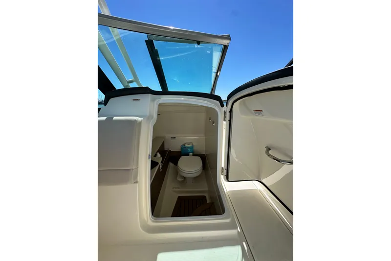 Slide: The Image of 2017 Boston Whaler 270 Vantage boat interior with open door revealing compact marine toilet. - 27