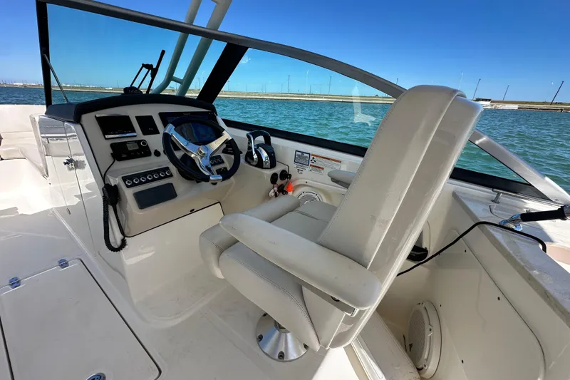 Slide: The Image of 2017 Boston Whaler 270 Vantage boat cockpit with steering wheel and controls, on calm water. - 35