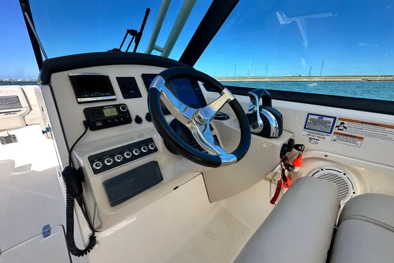 Slide: The Image of 2017 Boston Whaler 270 Vantage helm with steering wheel and controls, overlooking water. - 36