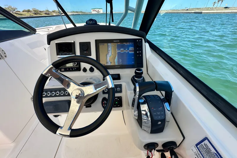 Slide: The Image of 2017 Boston Whaler 270 Vantage helm with steering wheel and navigation display on water. - 38
