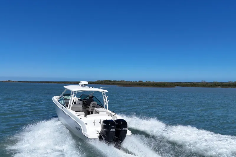 Slide: The Image of 2017 Boston Whaler 270 Vantage cruising on open water under clear blue skies. - 7