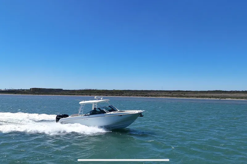 Slide: The Image of 2017 Boston Whaler 270 Vantage cruising on open water under clear blue sky. - 8
