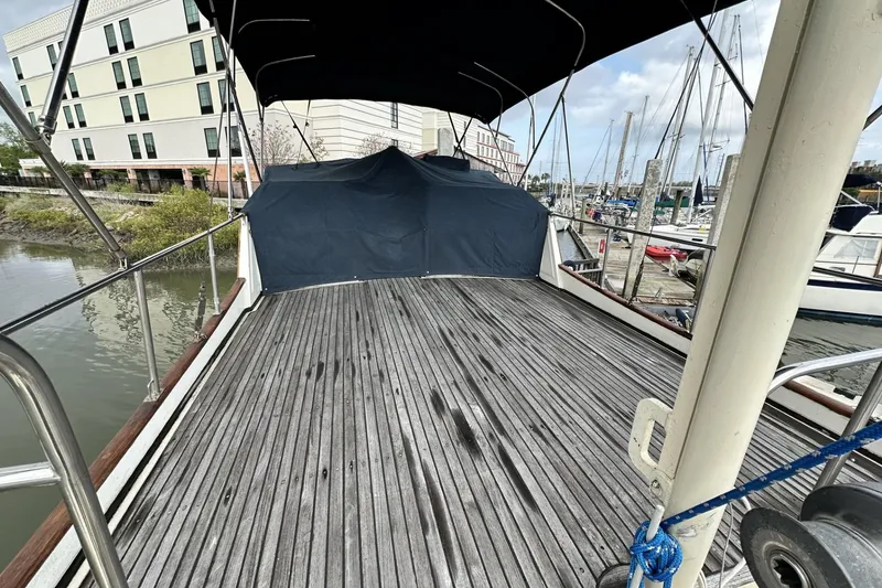 Slide: The Image of 1979 Grand Banks 42 Classic yacht deck with canopy, docked near modern buildings and marina. - 11