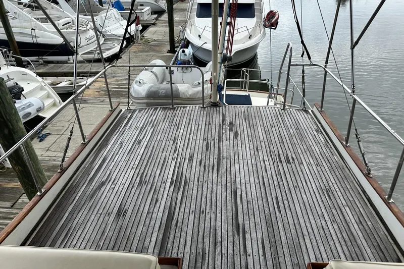 Slide: The Image of 1979 Grand Banks 42 Classic yacht deck at marina, featuring wooden flooring and moored boats. - 13