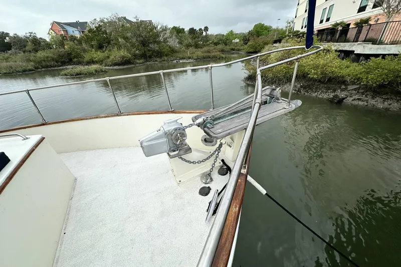 Slide: The Image of 1979 Grand Banks 42 Classic yacht bow with anchor, docked by a serene riverside. - 16