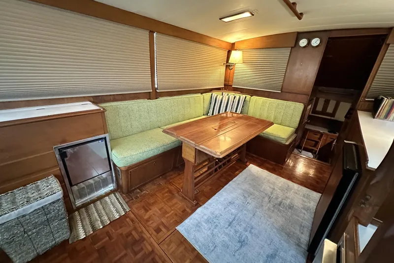 Slide: The Image of 1979 Grand Banks 42 Classic yacht interior with green seating, wooden table, and cozy lighting. - 19