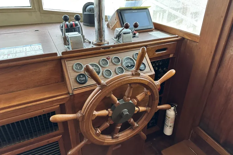 Slide: The Image of Wooden helm of a 1979 Grand Banks 42 Classic yacht with gauges and controls. - 24