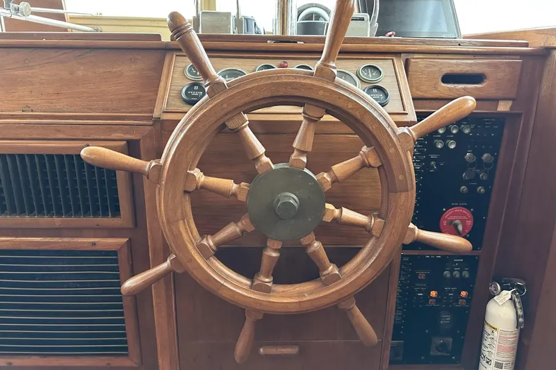 Slide: The Image of Wooden helm of a 1979 Grand Banks 42 Classic yacht, showcasing vintage nautical controls. - 25