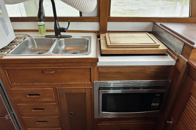 Slide: The Image of 1979 Grand Banks 42 Classic kitchen with double sink, microwave, and wooden cabinetry. - 28
