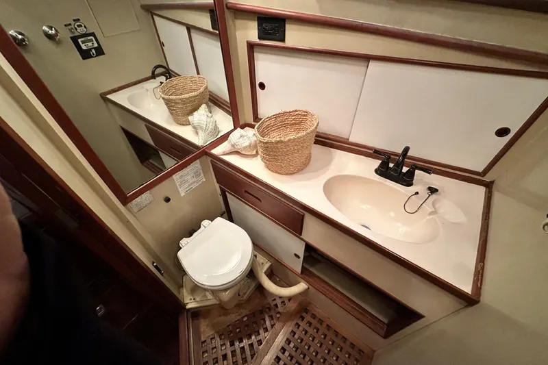 Slide: The Image of 1979 Grand Banks 42 Classic yacht bathroom with sink, toilet, and wicker basket. - 43