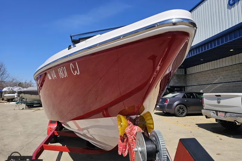 Slide: The Image of 2018 Baja 24 Outlaw boat with red hull on trailer, parked outdoors. - 13