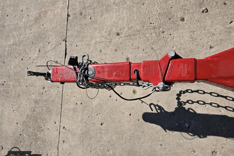 Slide: The Image of Red trailer hitch of a 2018 Baja 24 Outlaw boat on concrete surface. - 17
