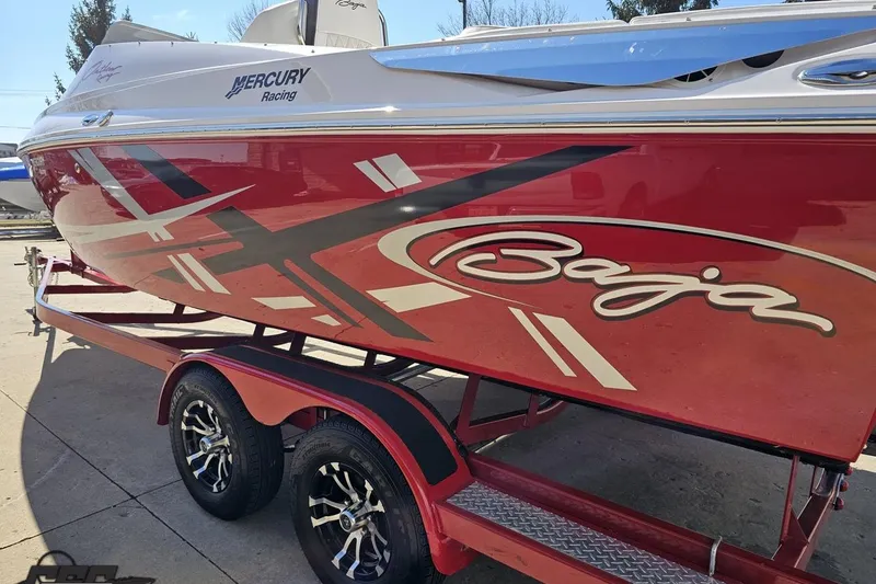 Slide: The Image of 2018 Baja 24 Outlaw boat with red and white graphics on a trailer. - 25