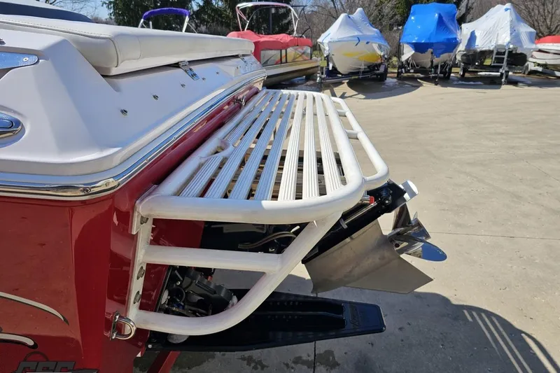 Slide: The Image of 2018 Baja 24 Outlaw boat with swim platform and propeller, parked among covered boats. - 26