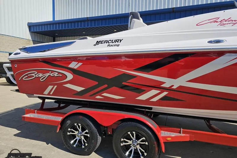 Slide: The Image of 2018 Baja 24 Outlaw boat with red and black graphics on a trailer. - 7